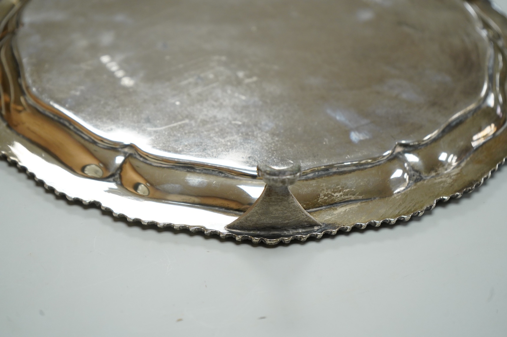 A George V silver salver, by Elkington & Co, of shaped circular form, with engraved crest, on three scroll feet, diameter 26.2cm, 18.7oz.